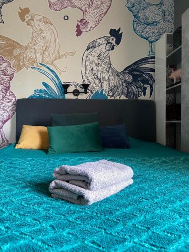 a bedroom with a bed with a green blanket and chickens on the wall at Siedlisko Kępina Zdrój in Ostrów
