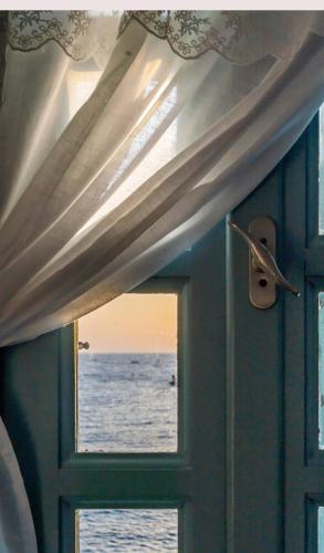 a window in a room with a view of the ocean at THE SHIP in Lefkos Karpathou