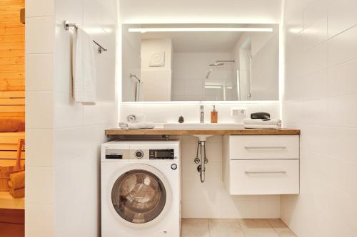 a bathroom with a washing machine and a sink at die Tauplitz Lodges - Wasserfall Lodge C1 by AA Holiday Homes in Tauplitz