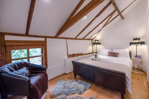 a bedroom with a bed and a chair and a window at The Hayloft, Clopton in Clopton