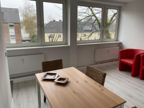 een kamer met een houten tafel, stoelen en ramen bij interaktiv . Appartements in Ratingen in Ratingen