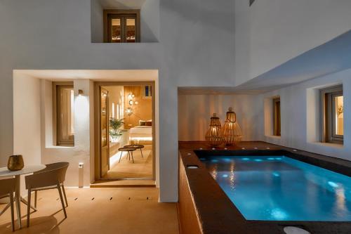 a large swimming pool in a living room with a table and a dining room at Domus Hestia Suites in Pirgos