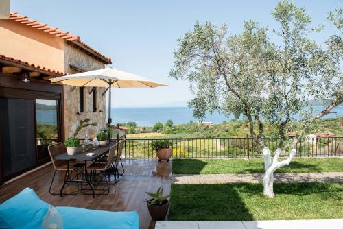 a patio with a table and an umbrella at Dandy Villas Nea Roda - Melodic Waves - Private - Pool - Parking - Cellar in Nea Roda
