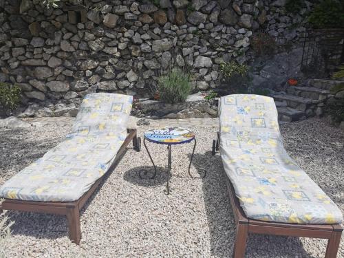 two benches and a table in front of a stone wall at Villa Laura amazing breakfast,private outdoor hot tub, Positano experience in Positano