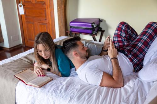 a man and a woman laying on a bed with a book at La Casona de Hermosa in Hermosa