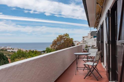a balcony with a table and chairs and the ocean at Vivenda Santiago in Sesimbra