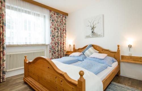 a bedroom with a wooden bed and a window at Tyrol Appartements in Ehrwald