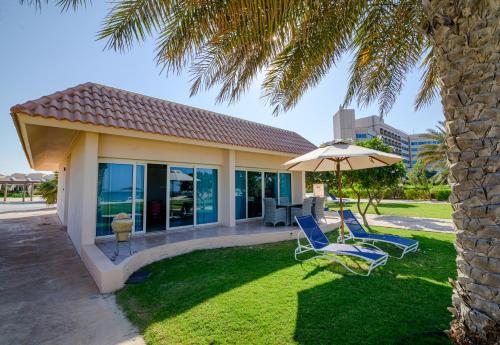 a pair of chairs and an umbrella on a lawn at Danat Jebel Dhanna Resort in Jebel Dhanna