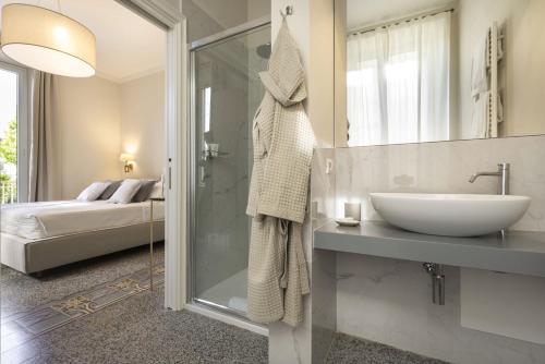 un bagno con lavandino e doccia e un letto di Villa La Tuia B&B a Lucca