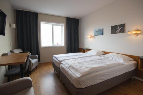 una camera d'albergo con un letto, una scrivania e una finestra di Hótel Búrfell a Vík