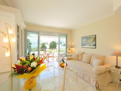 un soggiorno con divano e tavolo con fiori di Apartment Cristal Croisette-1 by Interhome a Cannes