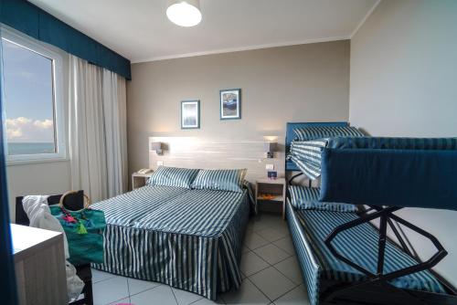a hotel room with two beds and a couch at HG Hotel Il Settebello in Marina di Cecina