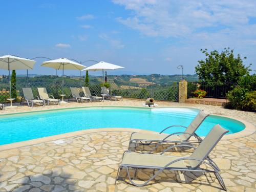 a swimming pool with two chairs and umbrellas at Holiday Home La Vecchia Pieve by Interhome in Castelfiorentino
