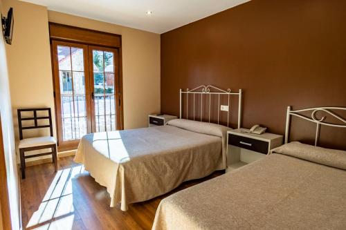 um quarto de hotel com duas camas e uma cadeira em Complejo Hotelero La Braña em San Isidro