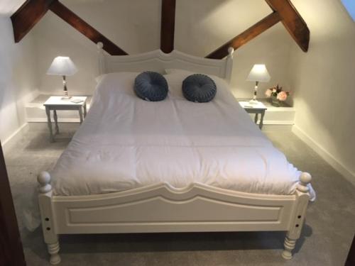 a bedroom with a white bed with two blue pillows at Beautiful 1 bed cottage in countryside in Tring