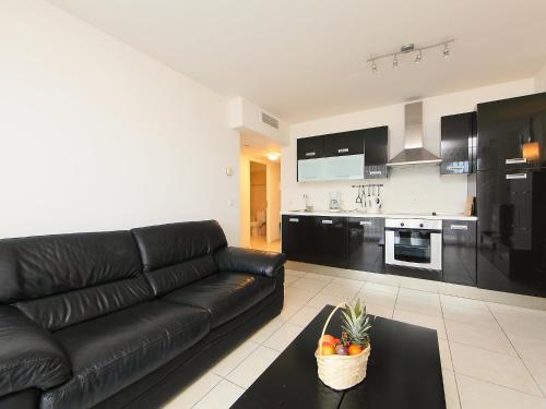 Il comprend un salon avec un canapé en cuir noir et une cuisine. dans l'établissement Apartment Casta Diva-1 by Interhome, à Cannes
