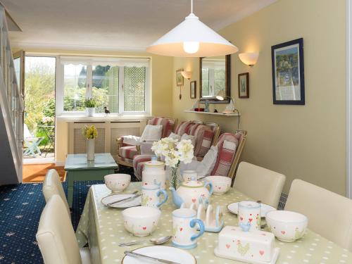 a dining room with a table with dishes and flowers on it at Holiday Home Ducks Dive by Interhome in Saint Keyne