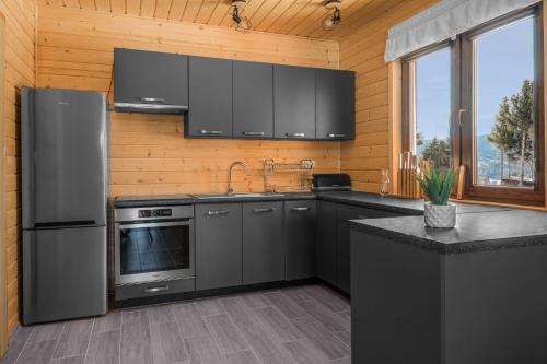 a kitchen with stainless steel appliances and black cabinets at Miodówka - komfortowy dom w górach in Glinka