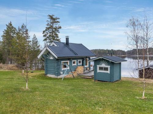uma pequena casa azul num relvado ao lado de um lago em Holiday Home Aurinkotupa by Interhome em Kokkosenlahti