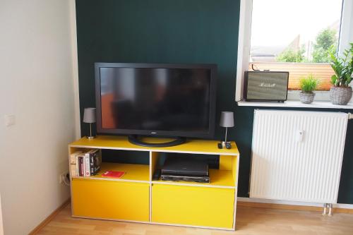 a tv on a yellow entertainment center with a yellow cabinet at Atelier Achtung Ausblick! in Rendsburg