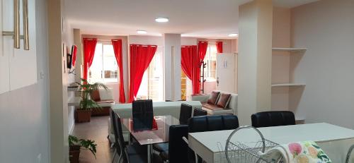 Habitación con cortinas rojas, mesa y sillas. en Casa Gaviota Dorada, en Baños