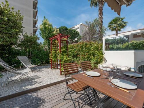 une terrasse en bois avec une table et des chaises ainsi qu'une aire de jeux dans l'établissement Apartment Villa Schneider by Interhome, à Cannes