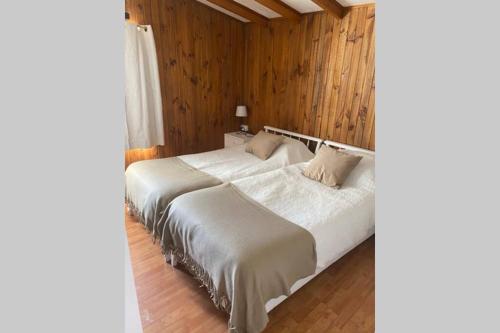 a bedroom with a large white bed with wooden walls at Refugio acogedor en Farellones in Santiago