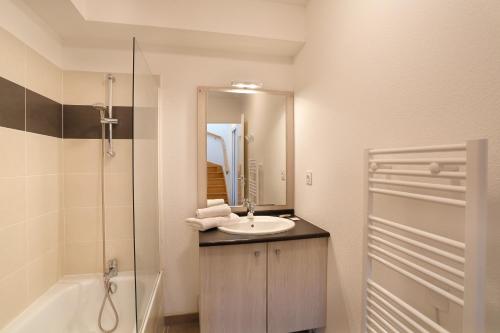 a bathroom with a sink and a shower and a mirror at Résidence Néméa le Domaine des Dunes in Mimizan-Plage