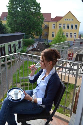 a woman sitting in a chair drinking a glass of wine at Hotel & Restaurant Zur Linde in Freital