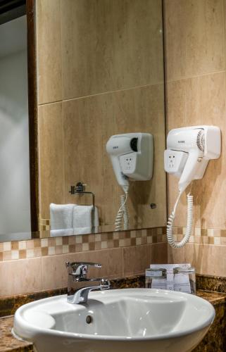 a bathroom sink with a hair dryer and a mirror at First Central Hotel Suites in Dubai