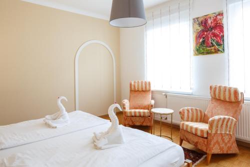 two swans on beds in a room with chairs at Pension Laubenhof in Mörbisch am See
