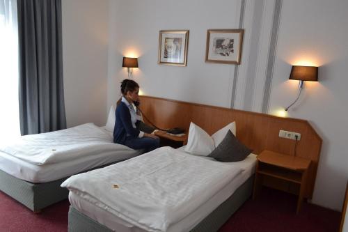a man in a hotel room with two beds at Hotel & Restaurant Zur Linde in Freital
