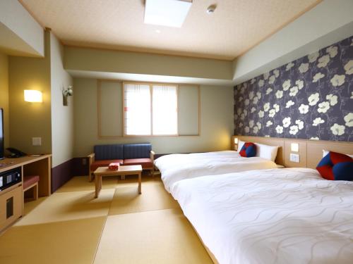 a hotel room with two beds and a tv at Onyado Nono Kanazawa in Kanazawa