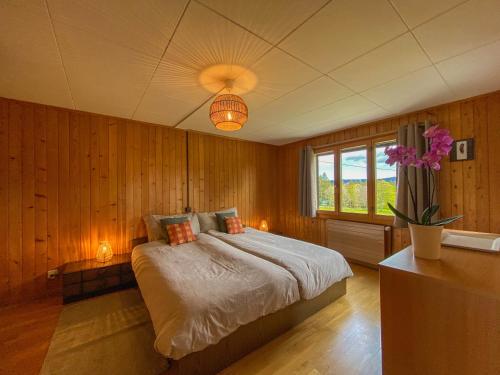 una camera da letto con un grande letto e una finestra di Chalet en pleine nature avec Spa a Le Locle