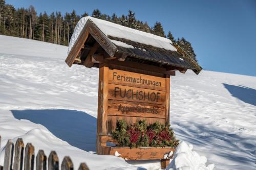 a wooden sign in the snow with flowers on it at Fuchshof in Perca