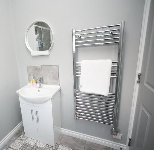 a white bathroom with a sink and a mirror at Apt3, 2 Antrim Gardens, Portrush with Seaview in Portrush