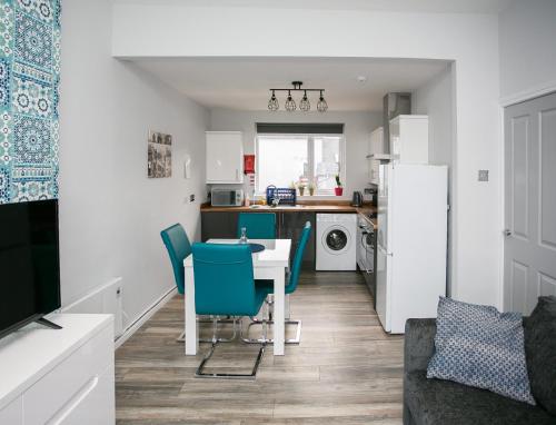 a kitchen and living room with a table and blue chairs at Apt3, 2 Antrim Gardens, Portrush with Seaview in Portrush