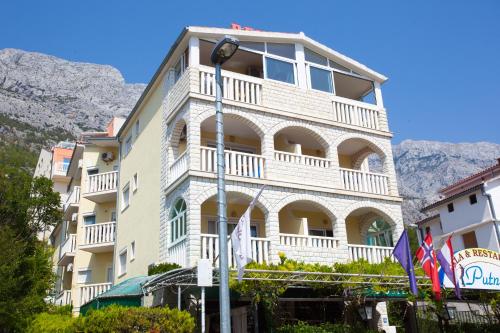 a large white building with balconies on a mountain at Apartmani Putnik in Baška Voda