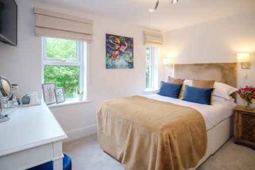a white bedroom with a large bed with blue pillows at The Water Rat in Ironbridge