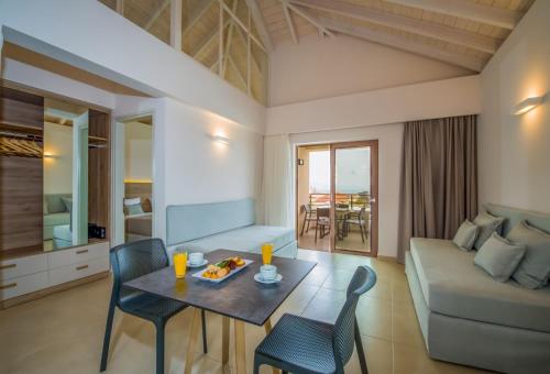 a living room with a table and chairs and a couch at Stefan Village Hotel in Agia Marina Nea Kydonias