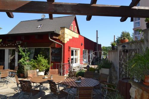 a patio with tables and chairs and a red building at Hotel & Restaurant Zur Linde in Freital