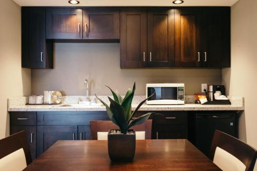 a kitchen with wooden cabinets and a table with a microwave at Holiday Inn and Suites East Peoria by IHG in Peoria