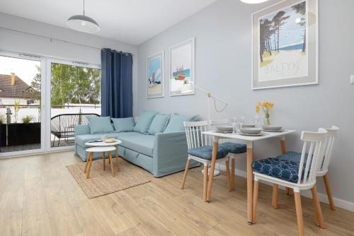 a living room with a blue couch and a table at Apartamenty Sunset Resort by Renters in Grzybowo
