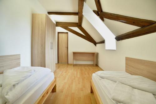 two beds in a room with wooden floors and beams at Pivovarský dvůr Lipan in Týn nad Vltavou