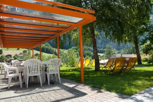 a group of chairs and tables under an orange canopy at Valley Hostel in Lauterbrunnen