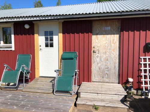 two lawn chairs sitting on the porch of a house at Three Rooms stuga i stugby near National Park in Undenäs