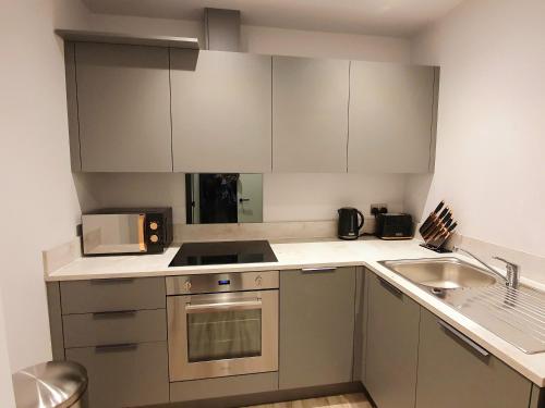 a small kitchen with white cabinets and a sink at Stansted Airport Luxury Apartment Bishops Stortford Millars One Loft 2 in Bishops Stortford