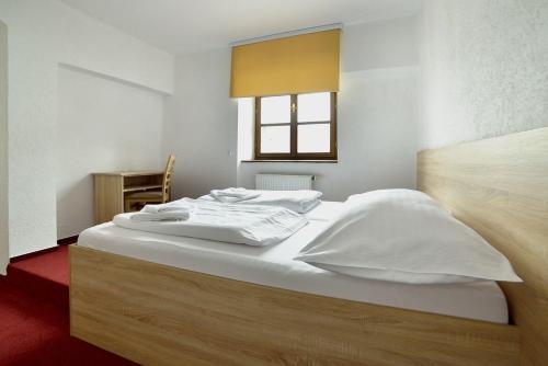 a bedroom with a bed with white sheets and a window at Pivovarský dvůr Lipan in Týn nad Vltavou