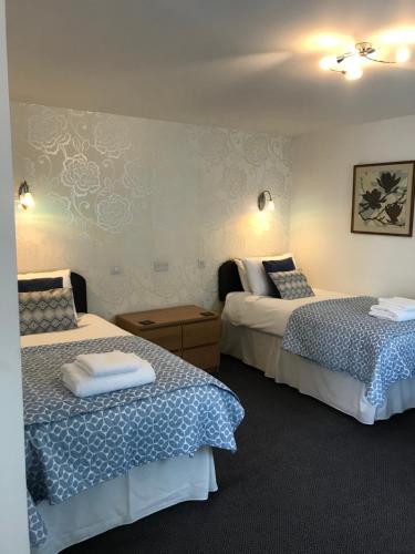 a hotel room with two beds with blue and white sheets at The Green Man in Leek