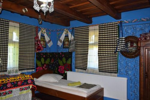 ein Schlafzimmer mit einem Bett in einem Zimmer mit Fenstern in der Unterkunft Pensiunea Inima Maramureșului in Breb